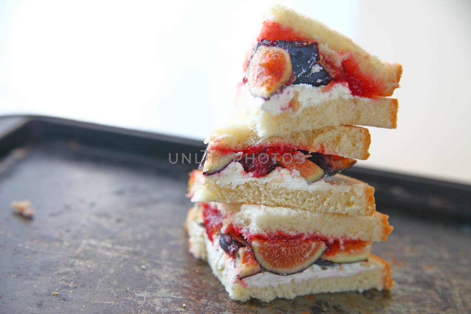 Fresh figs with cream cheese and jam sandwich cut into triangles and stacked