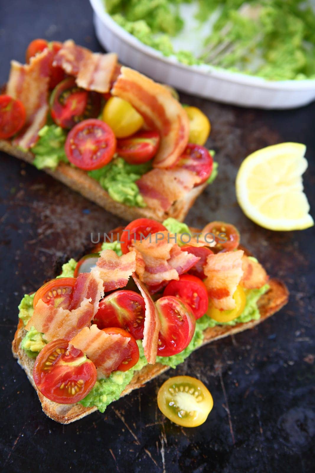 Bacon and cherry tomatoes on toast with mashed avocado