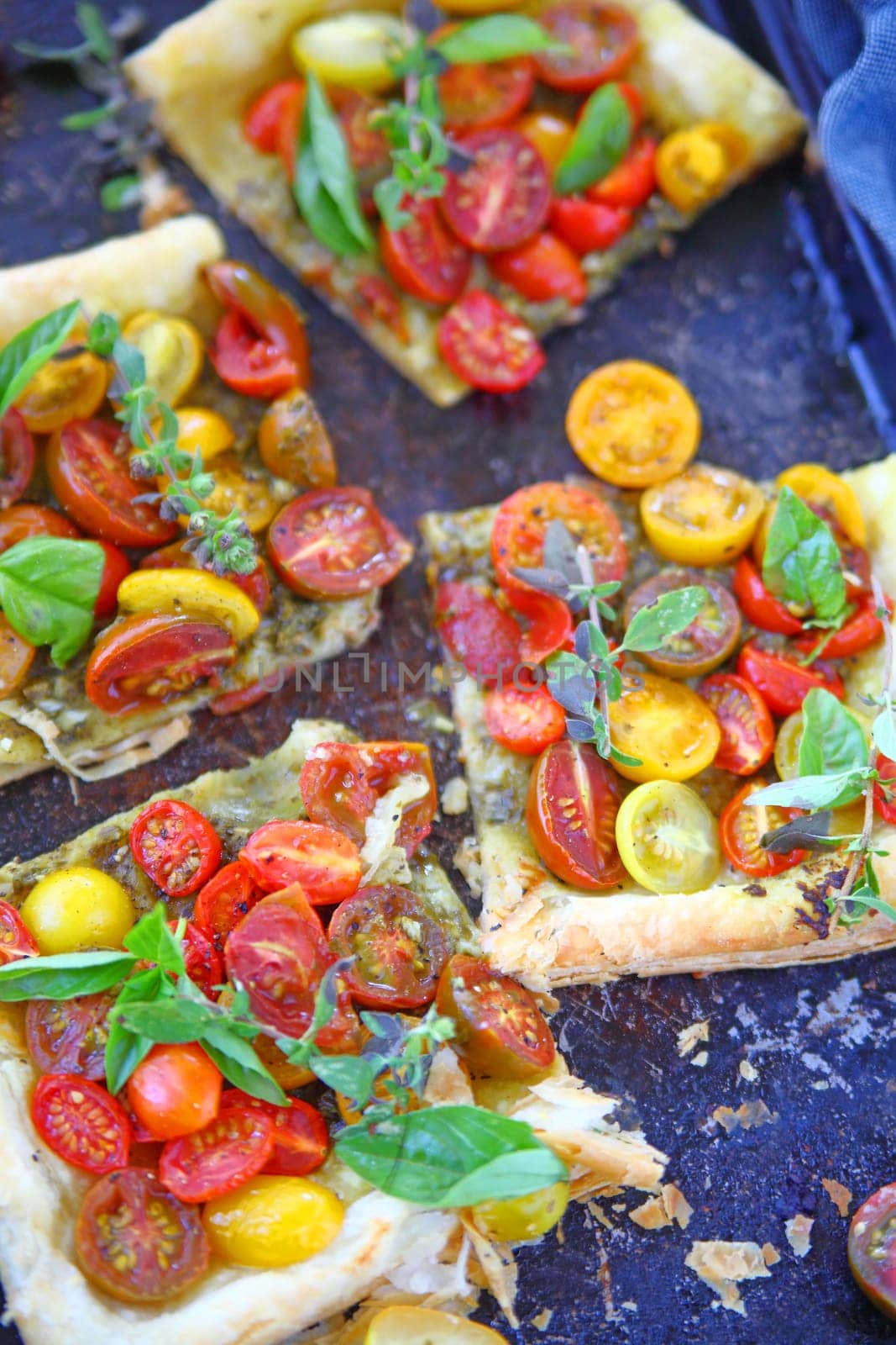 A cherry tomato tart with fresh herbs cut into servings