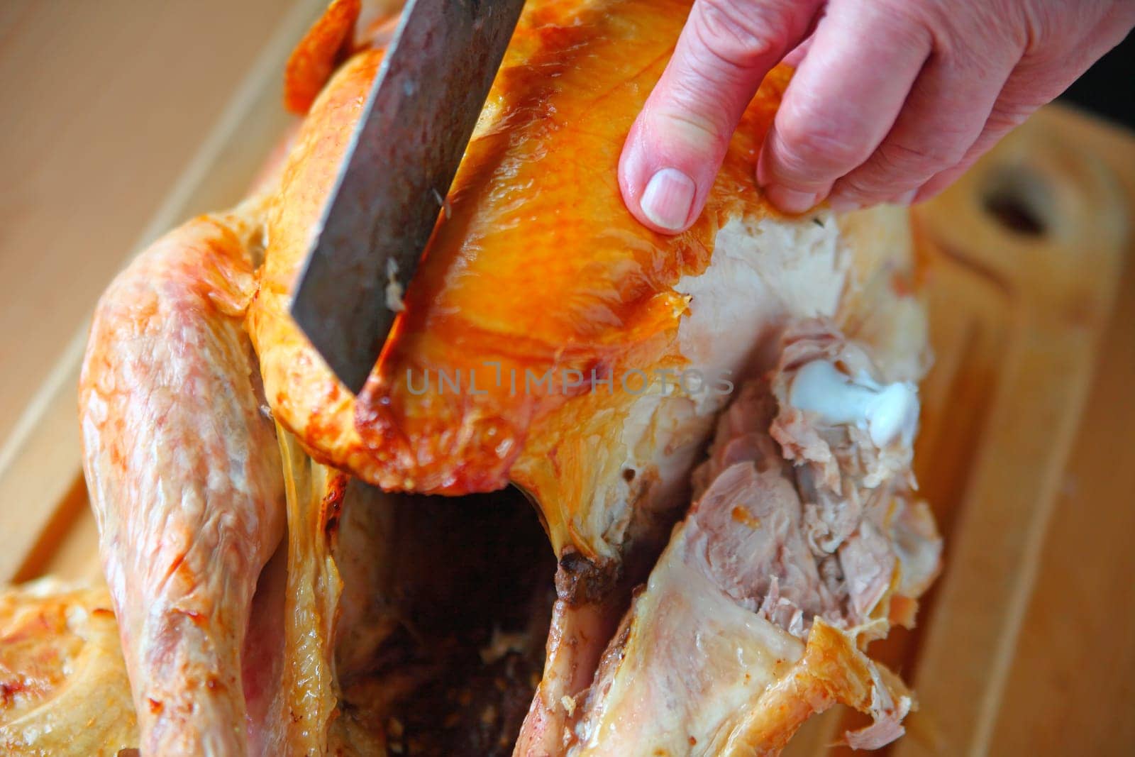A man holds a turkey steady as he cuts into the breast