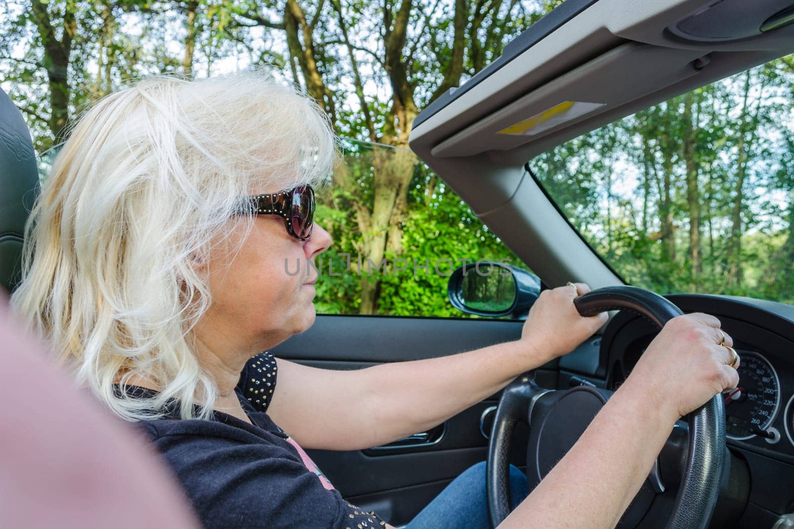 Happy woman driving a convertible in a classic sports car