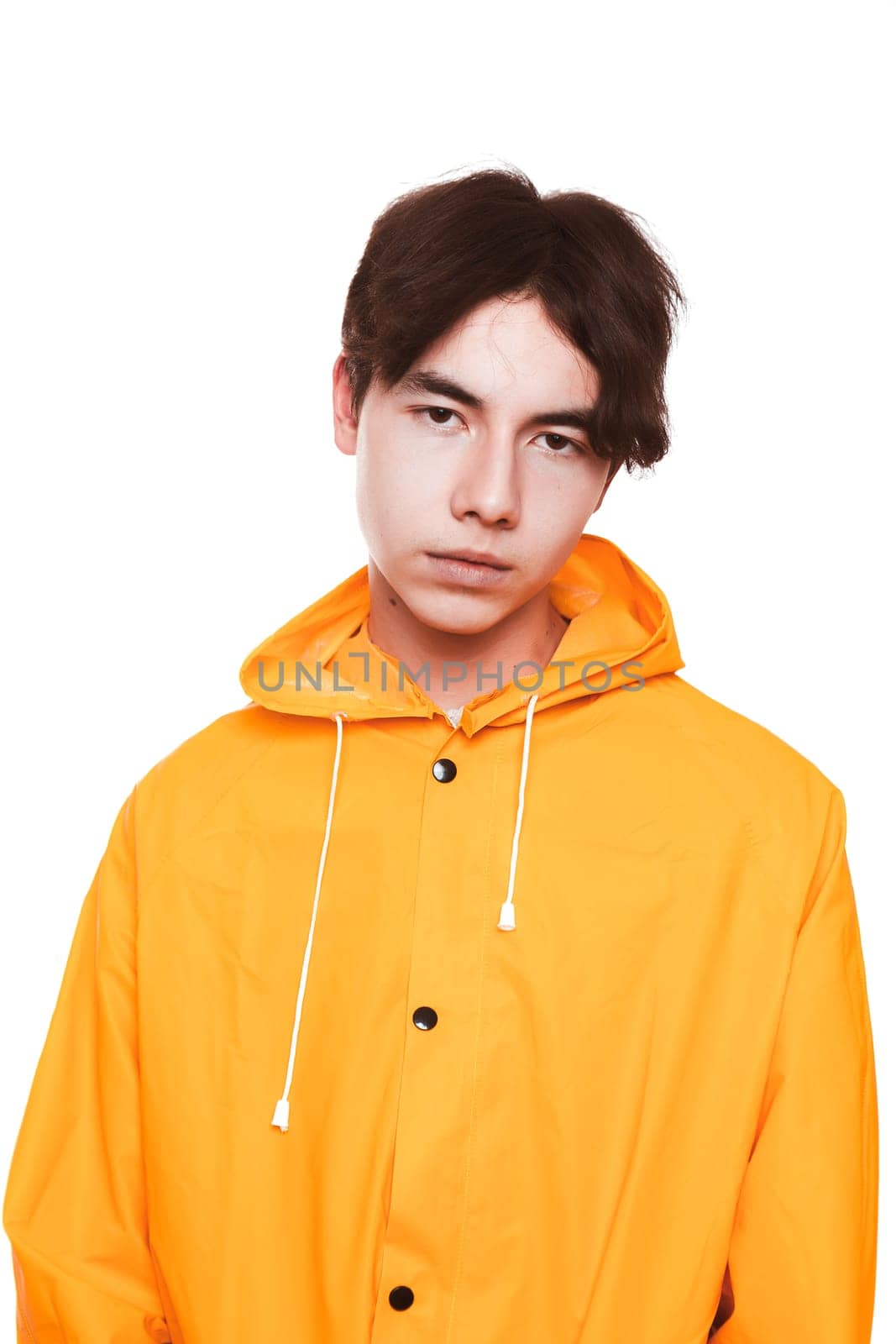 portrait of a teen guy in a yellow raincoat brunette in the studio.