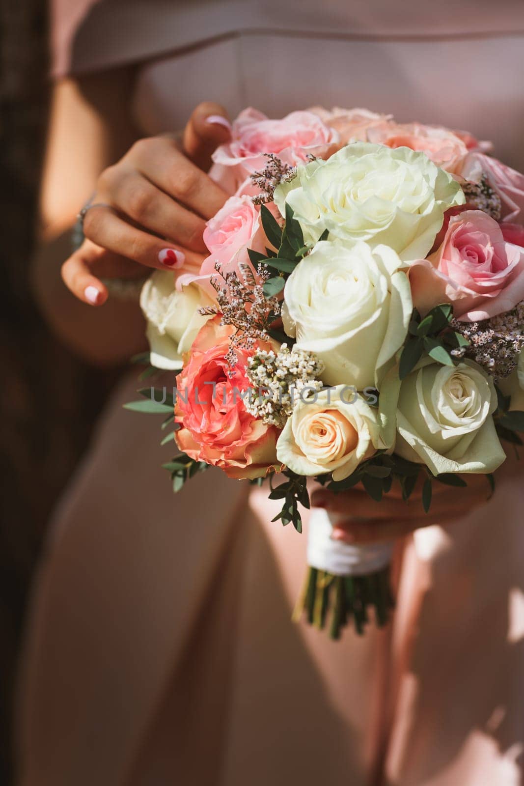 beautiful wedding bouquet of cream roses in hands of the bride.