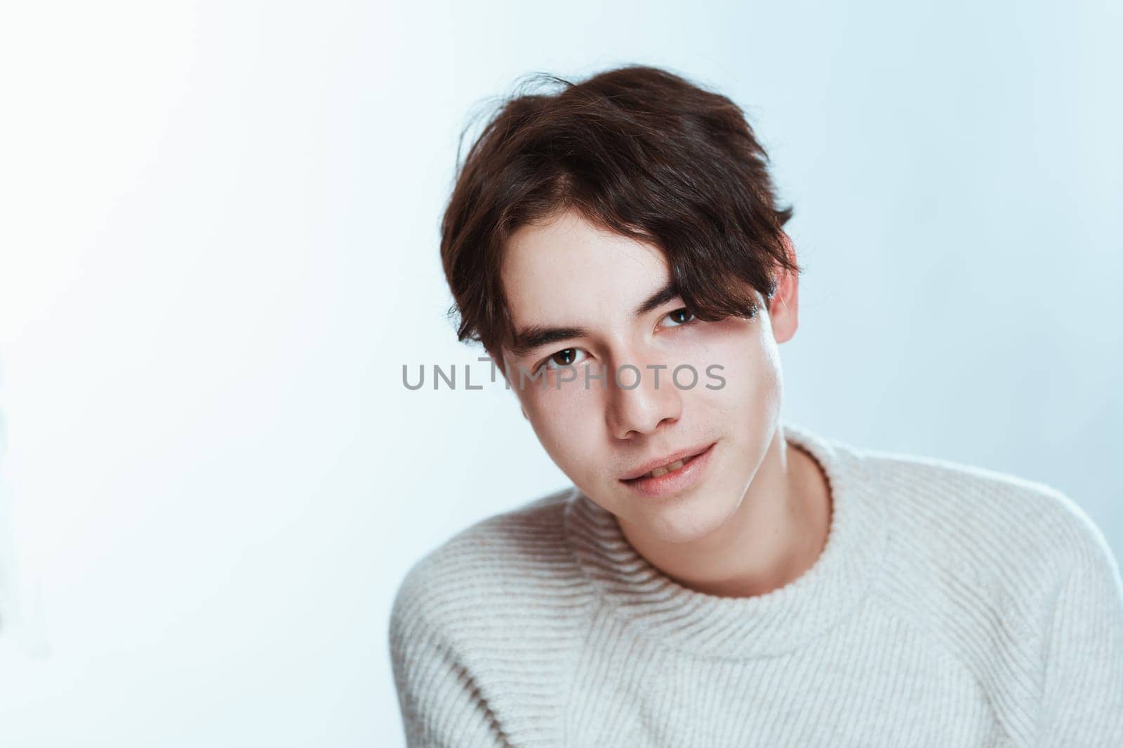 Studio portrait young man in grey sweater on white background.