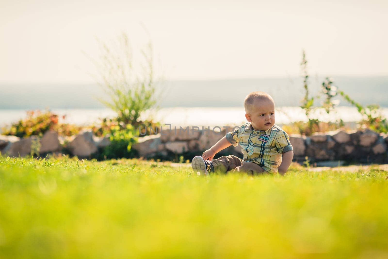 Baby boy on green grass nature background.