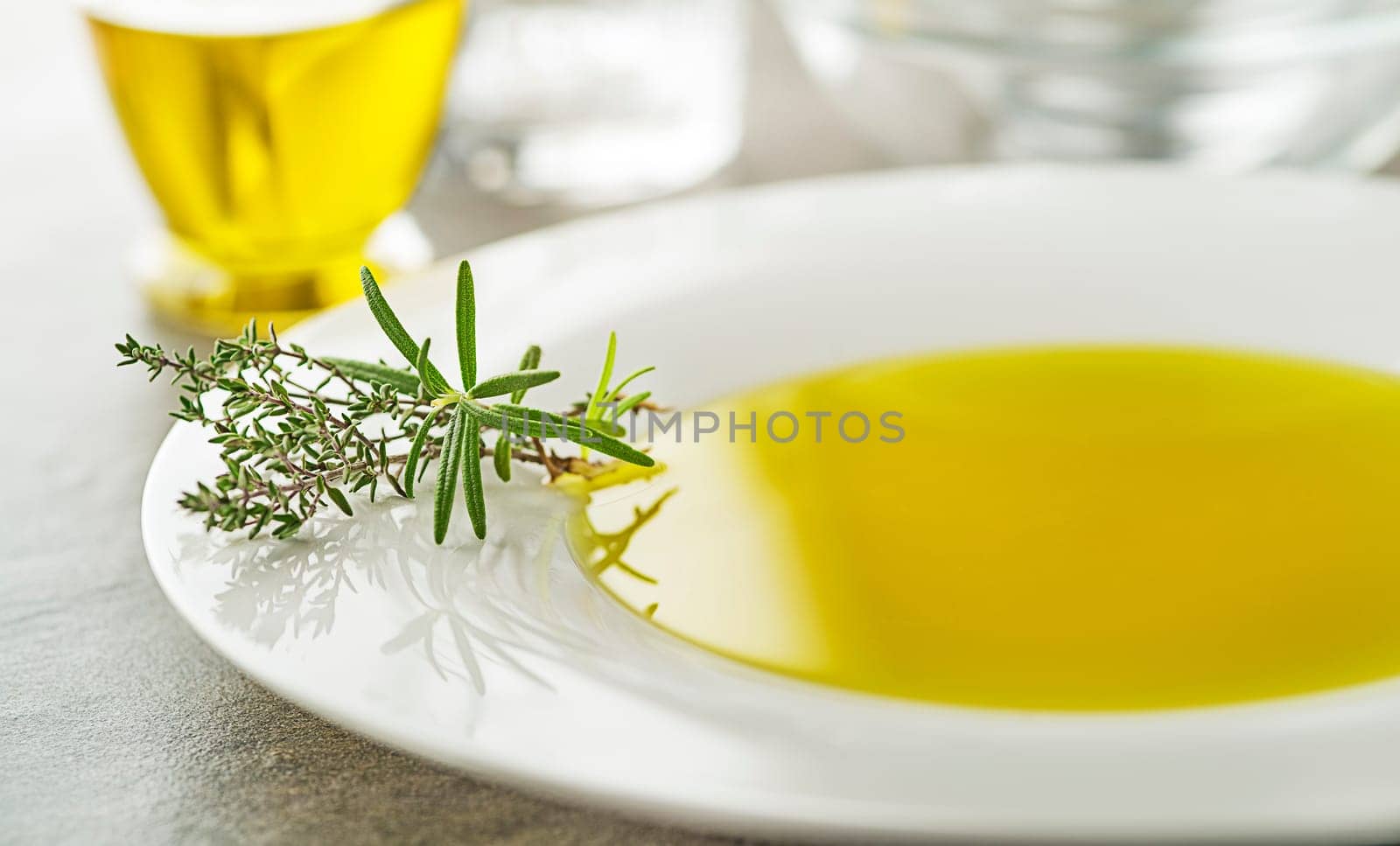 Healthy olive oil with herbs pouring in to plate close up