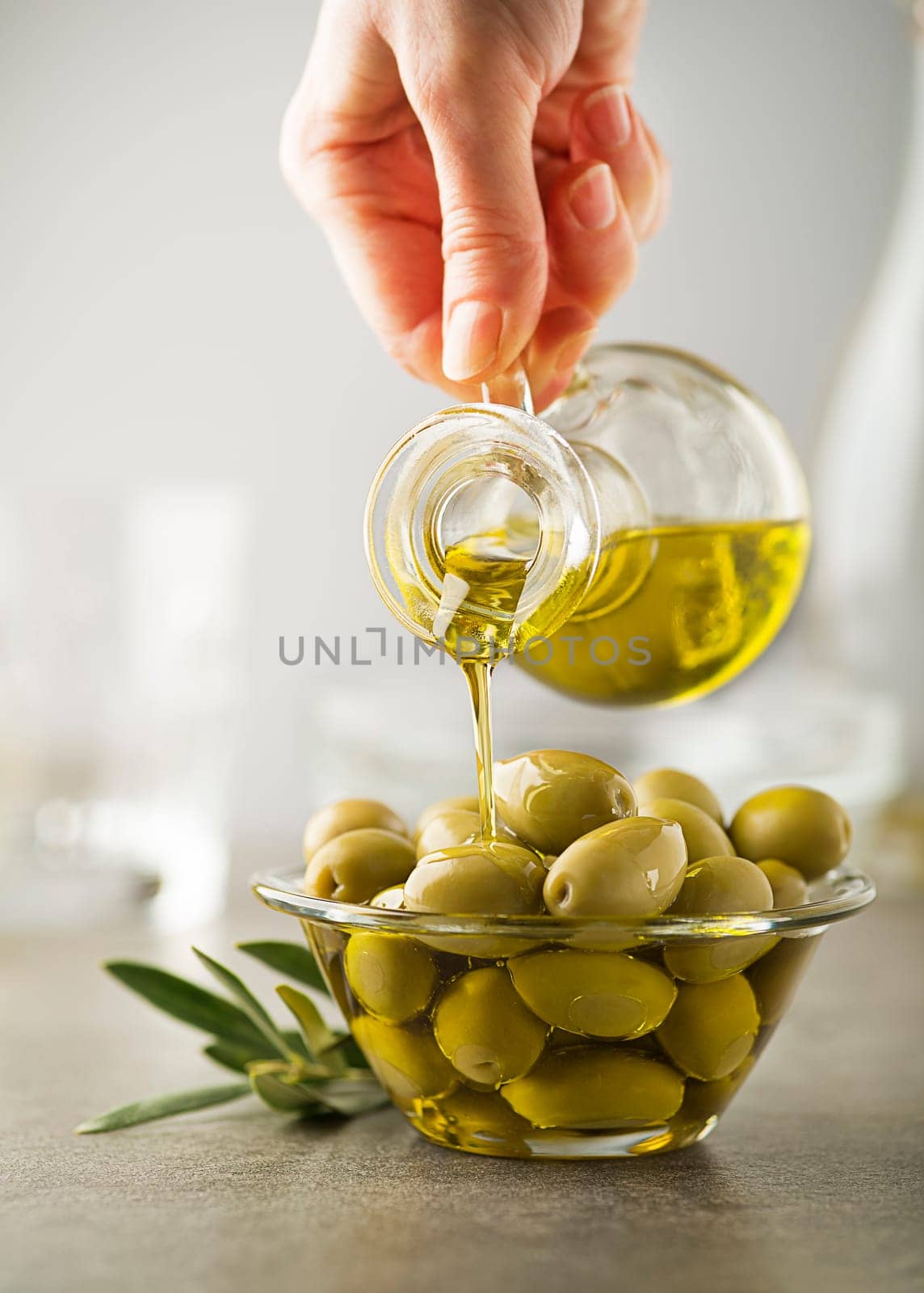 Organic olive oil. Bottle of Extra virgin oil pouring in to glass bowl with olives