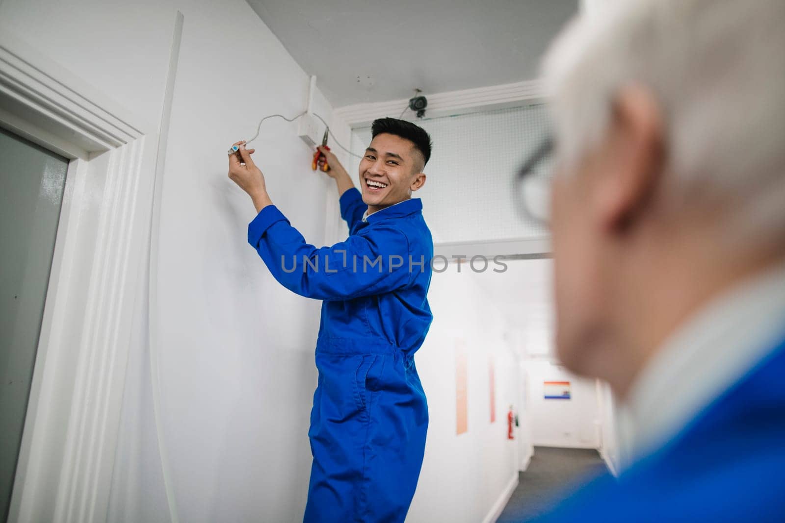 Trainee electrician is fitting a security camera with assistance from his tutor.