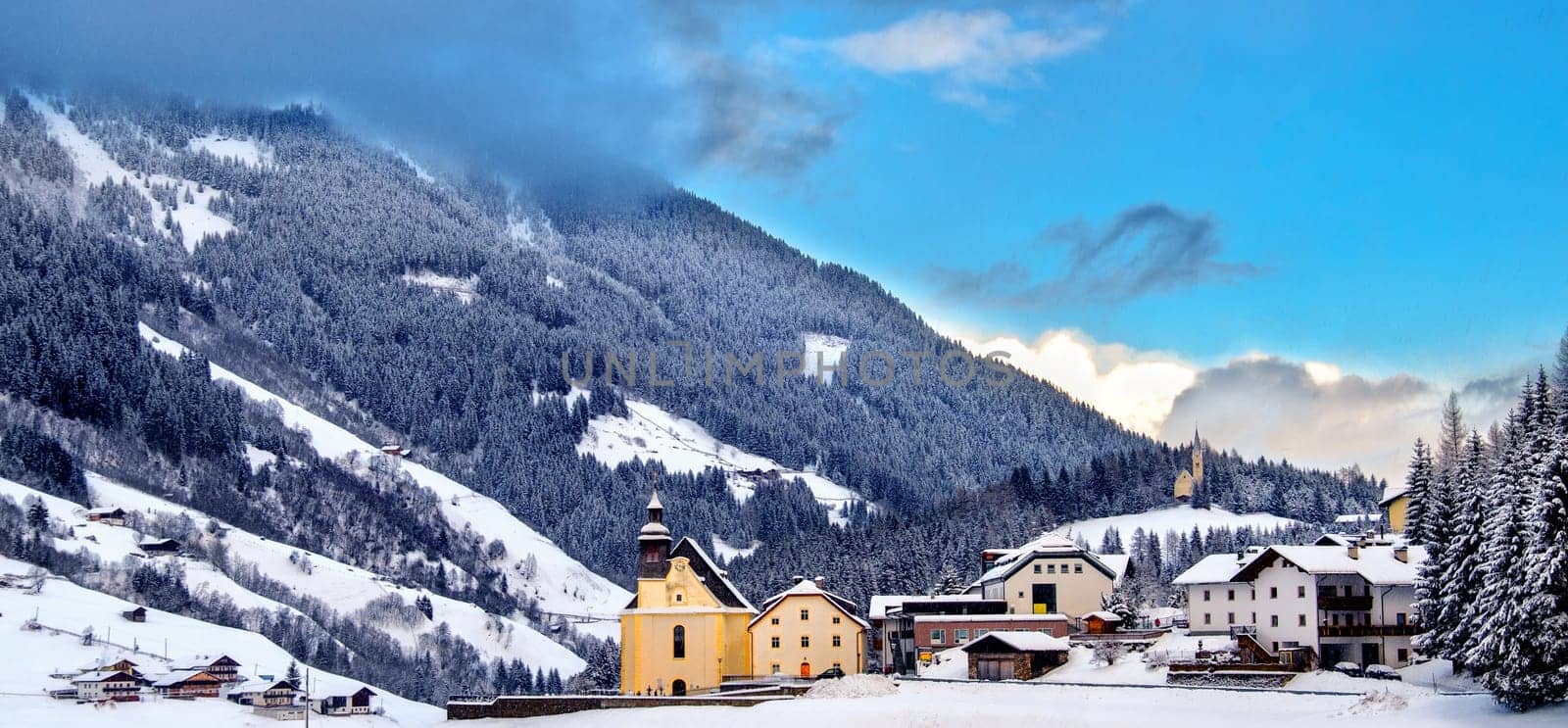panoramic overview of the little church with the snowy valley on a beautiful winter sunny day in Trentino Alto Adige - Italy