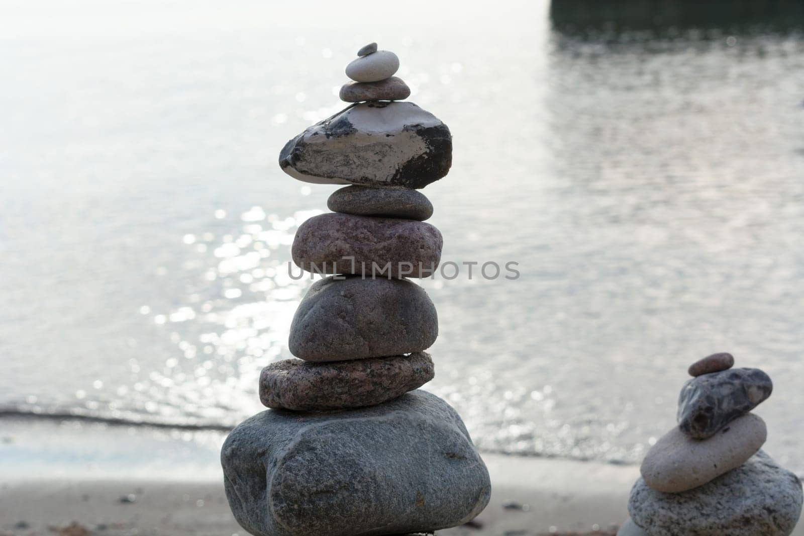 Stones stacked on top of each other on the beach with sea view in the background