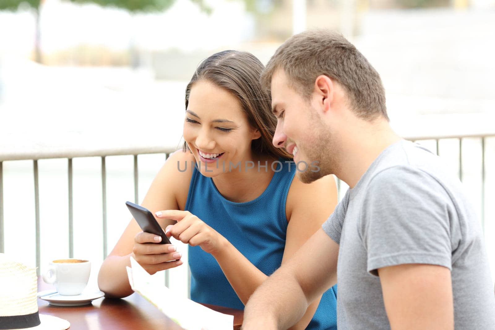 Portrait of a happy couple of tourists planning travel sitting in a coffee shop