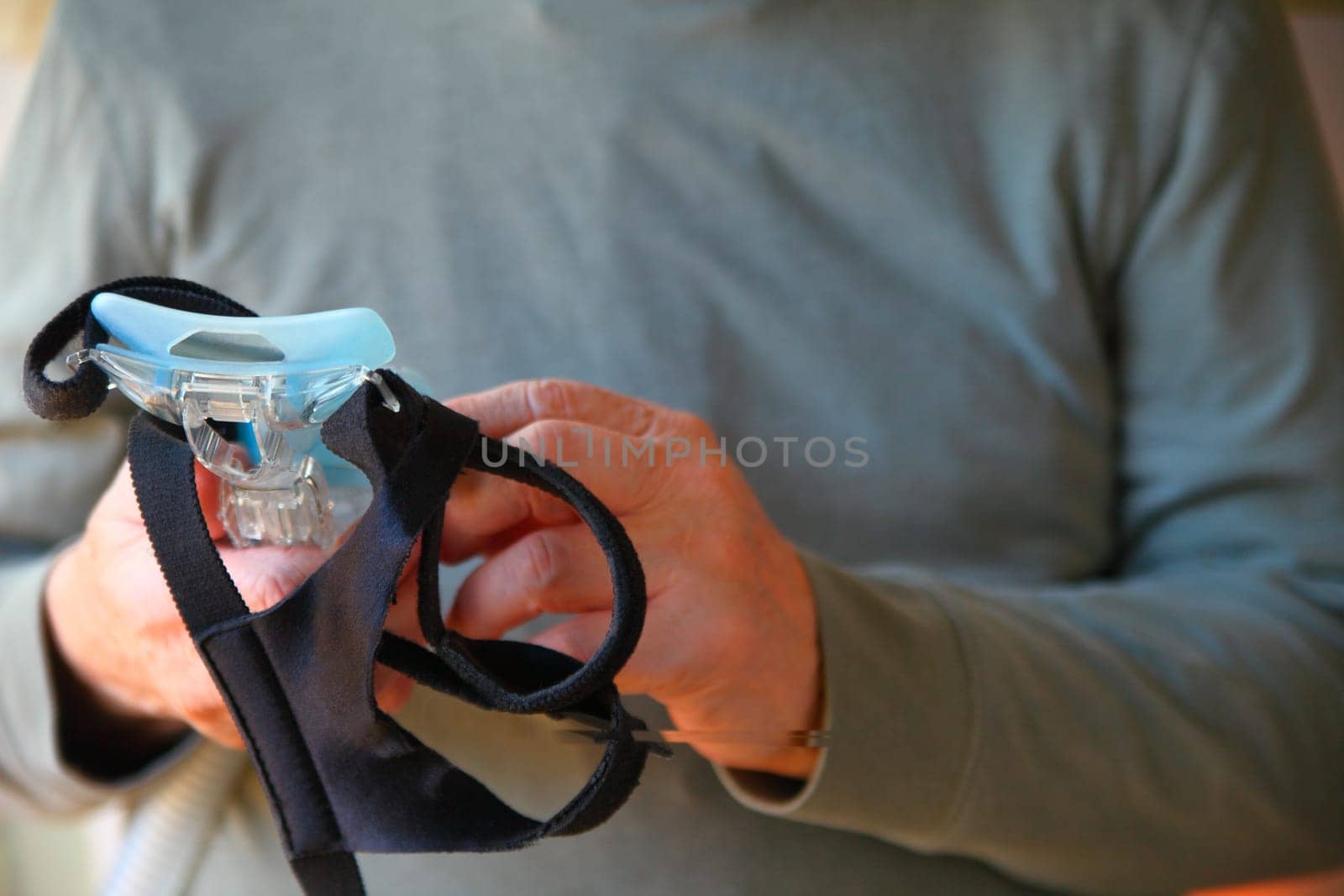 A man holds his sleep apnea face mask and headgear