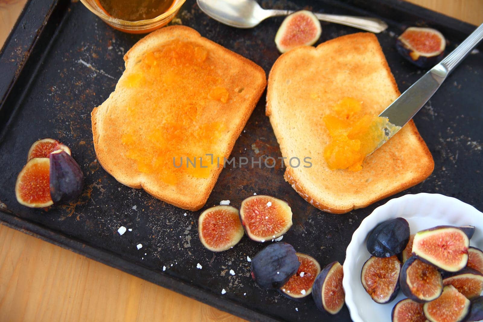 Overhead view of toast, apricot jam and fresh figs on a baking pan