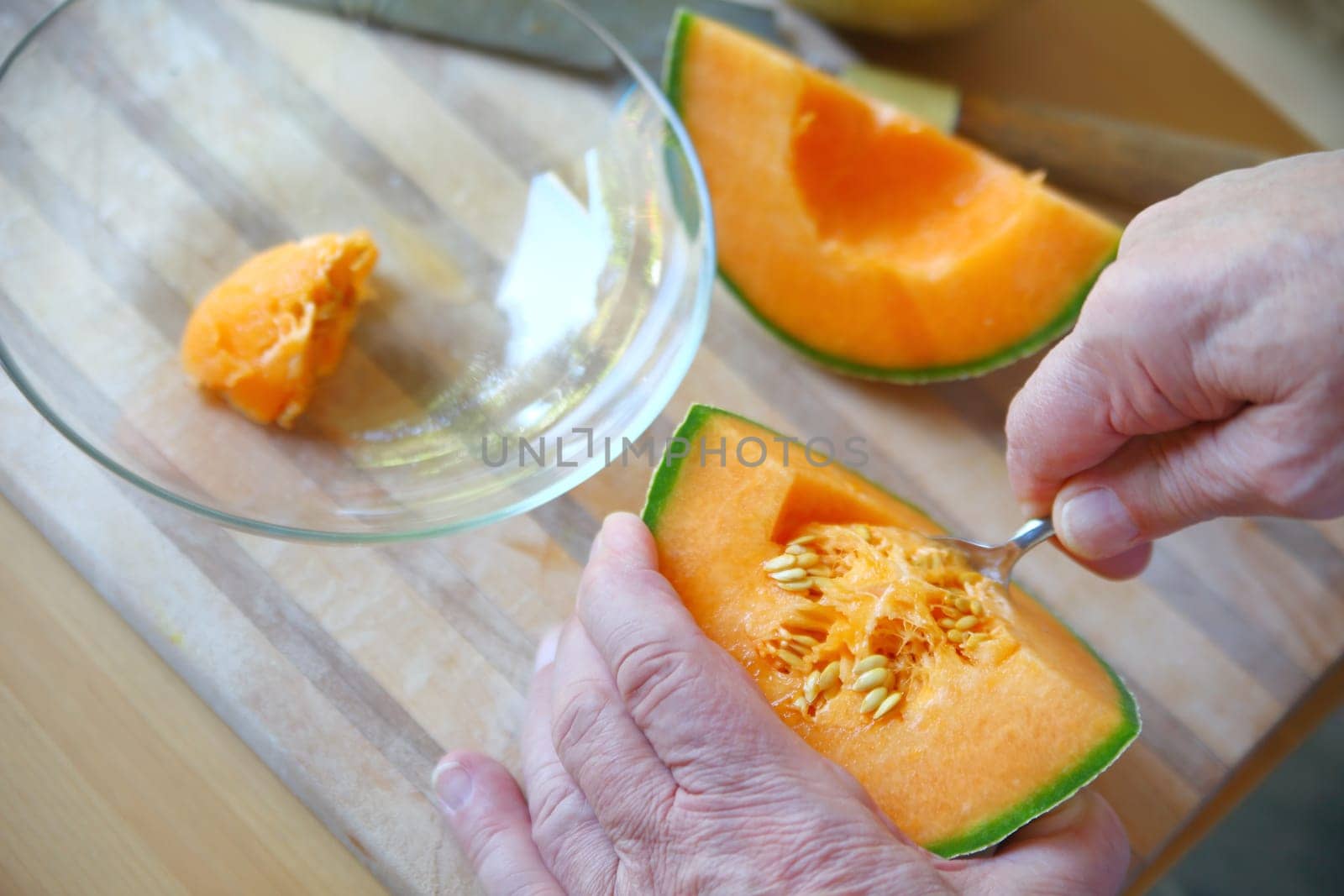 Older man scoops cantaloupe seeds with spoon