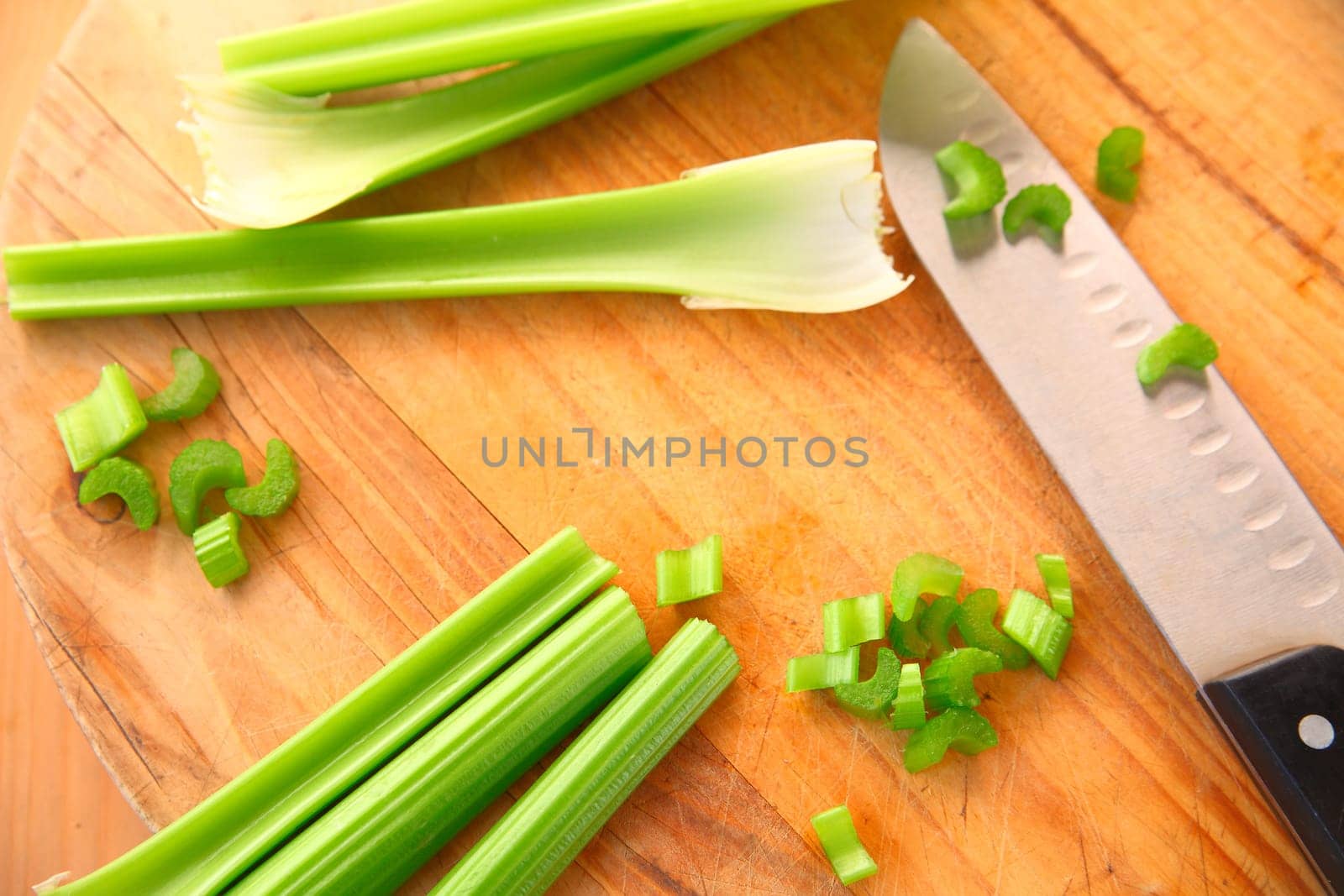 Celery stalks on a cutting board with kitchen knife