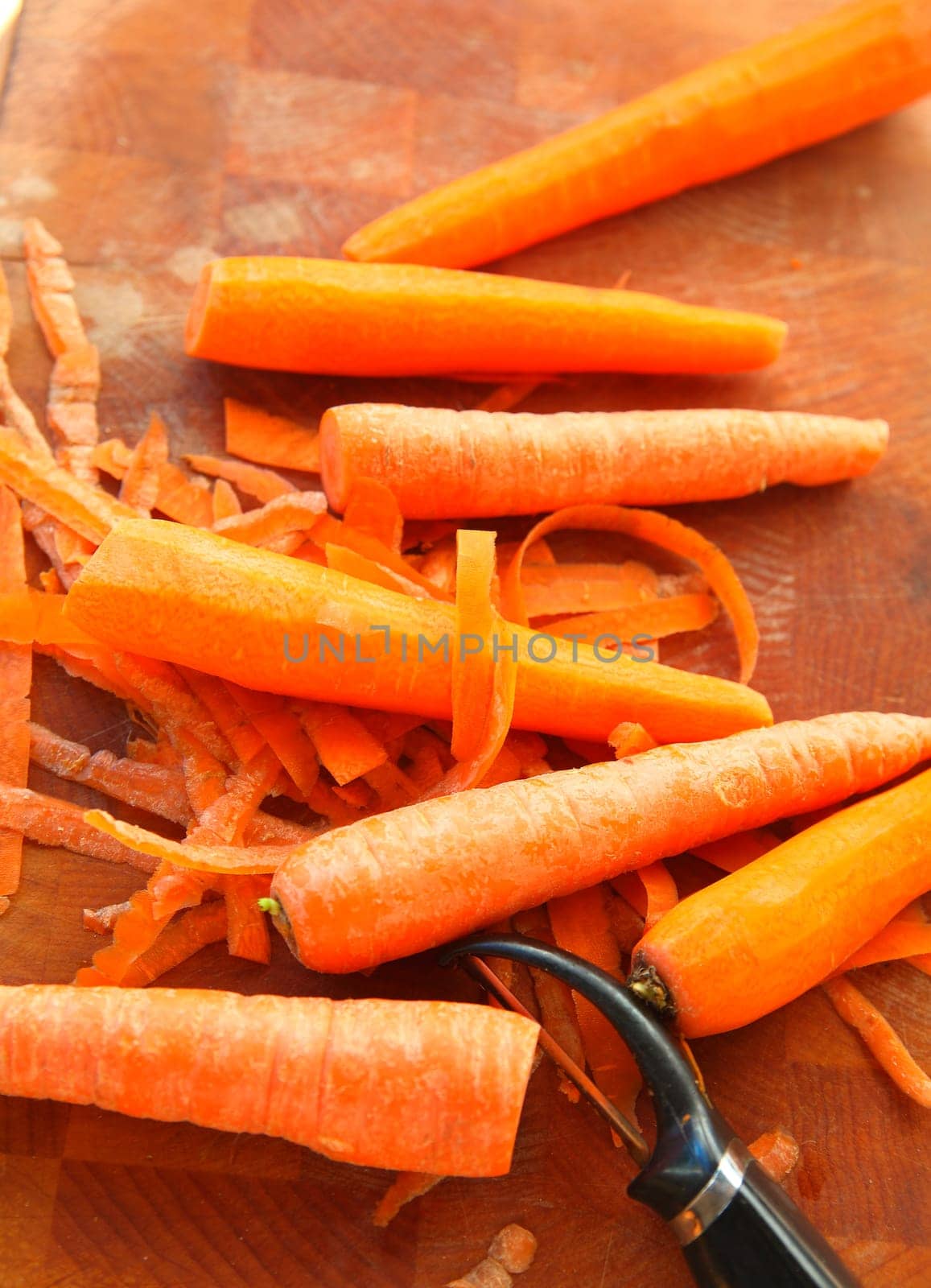 Vertical view of raw carrots and peeler with room for text