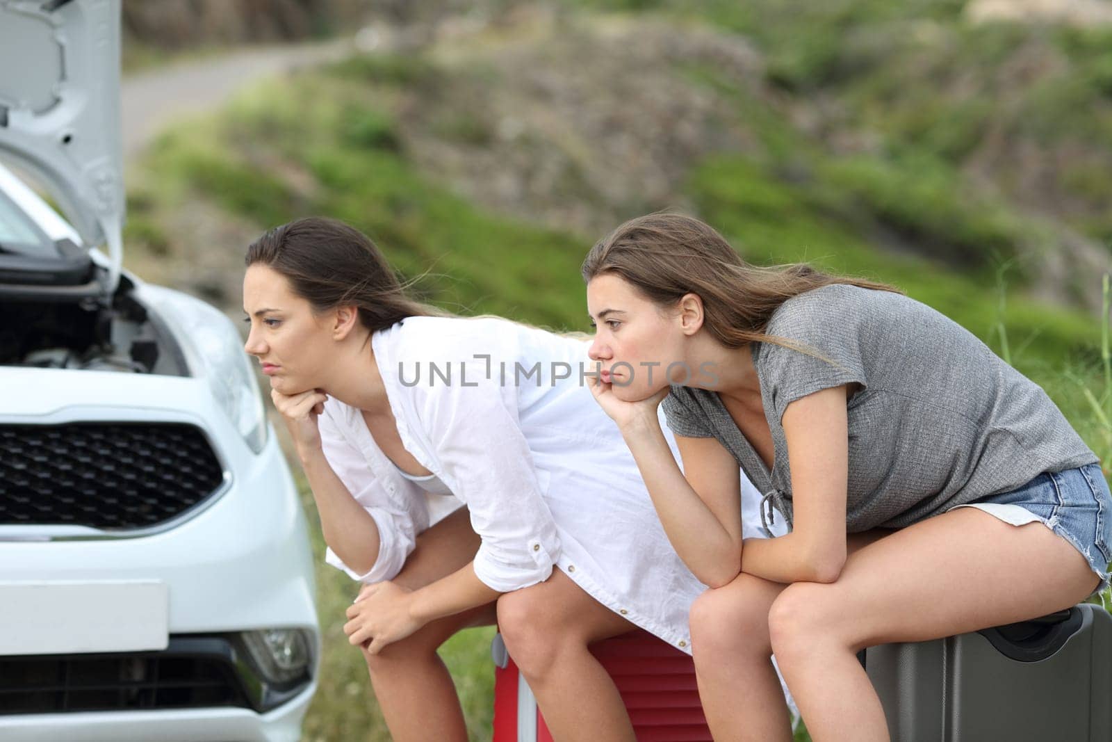 Two frustrated car drivers waiting for assistance after breakdown on summer holidays