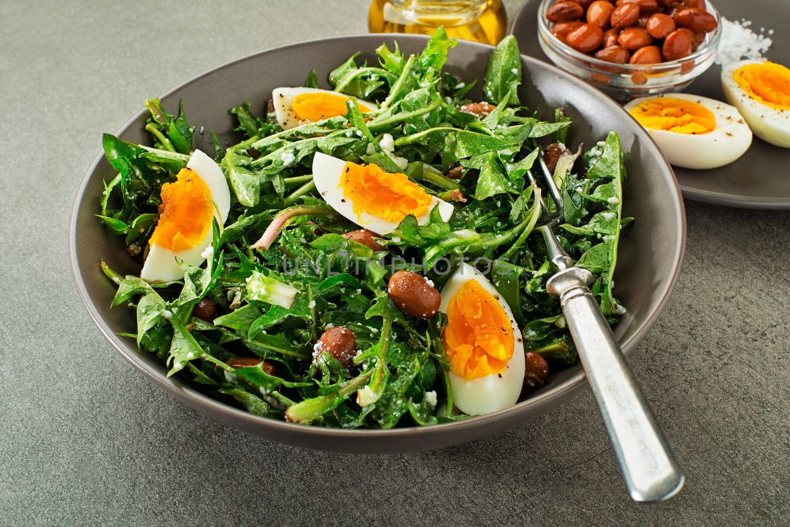 Fresh healthy dandelion salad with eggs and beans close up