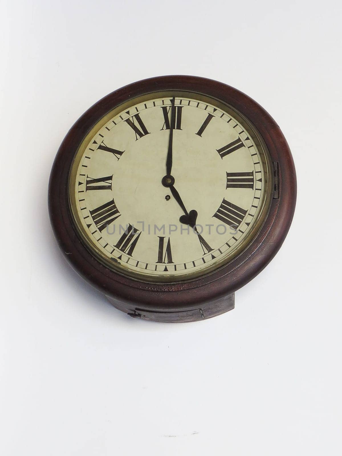 Old clock railway station of last century, wooden, circular with Roman numerals, on white background.
