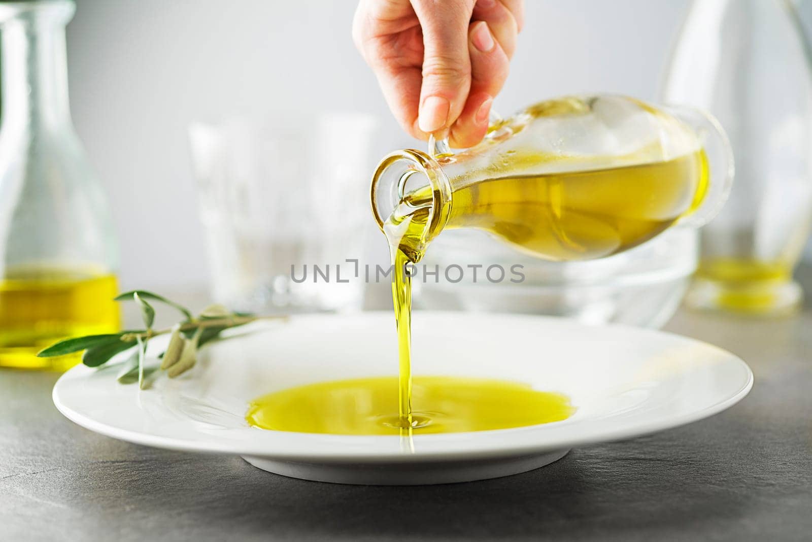 Bottle of healthy virgin olive oil pouring to plate close up