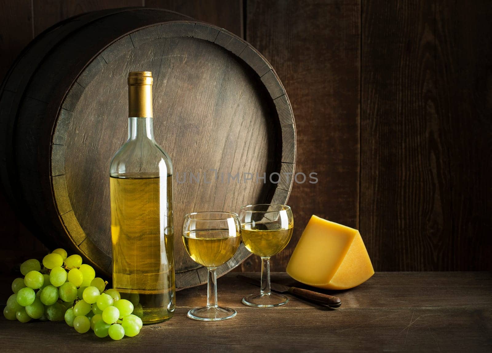 Bottle of white wine with cheese food on old board and barrel. Wine bottle mockup.