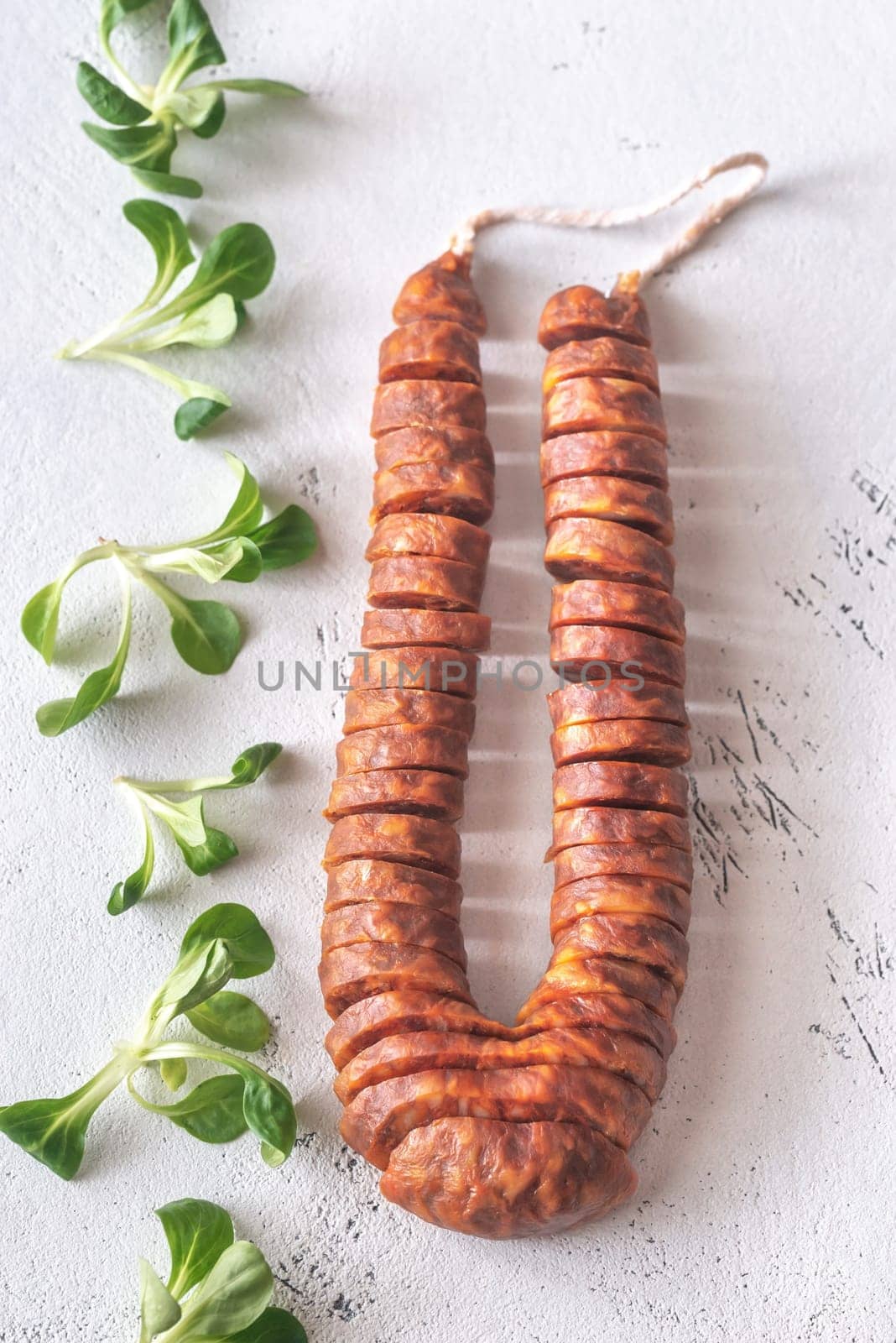 Spanish chorizo with fresh lettuce on the white wooden background