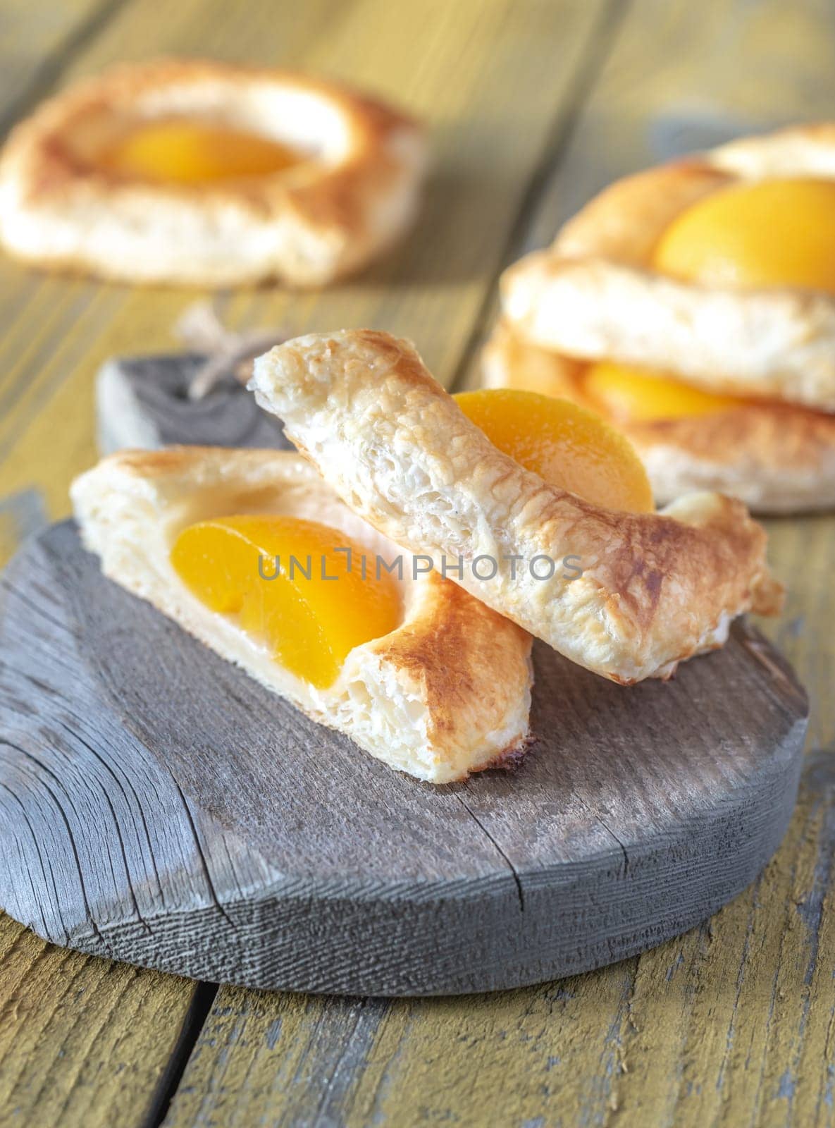Puff pastry with canned peaches on the wooden table
