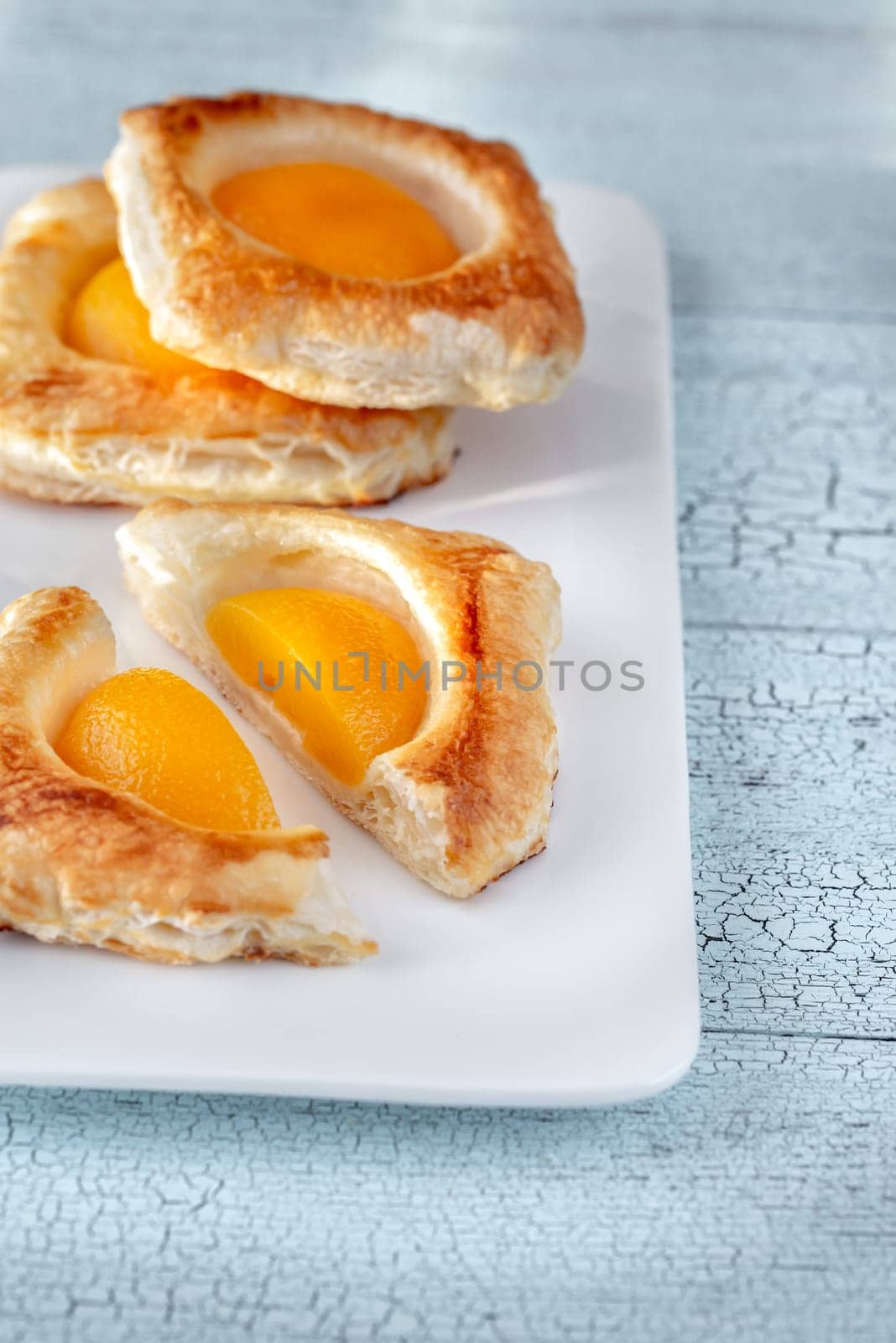 Puff pastry with canned peaches on the wooden table