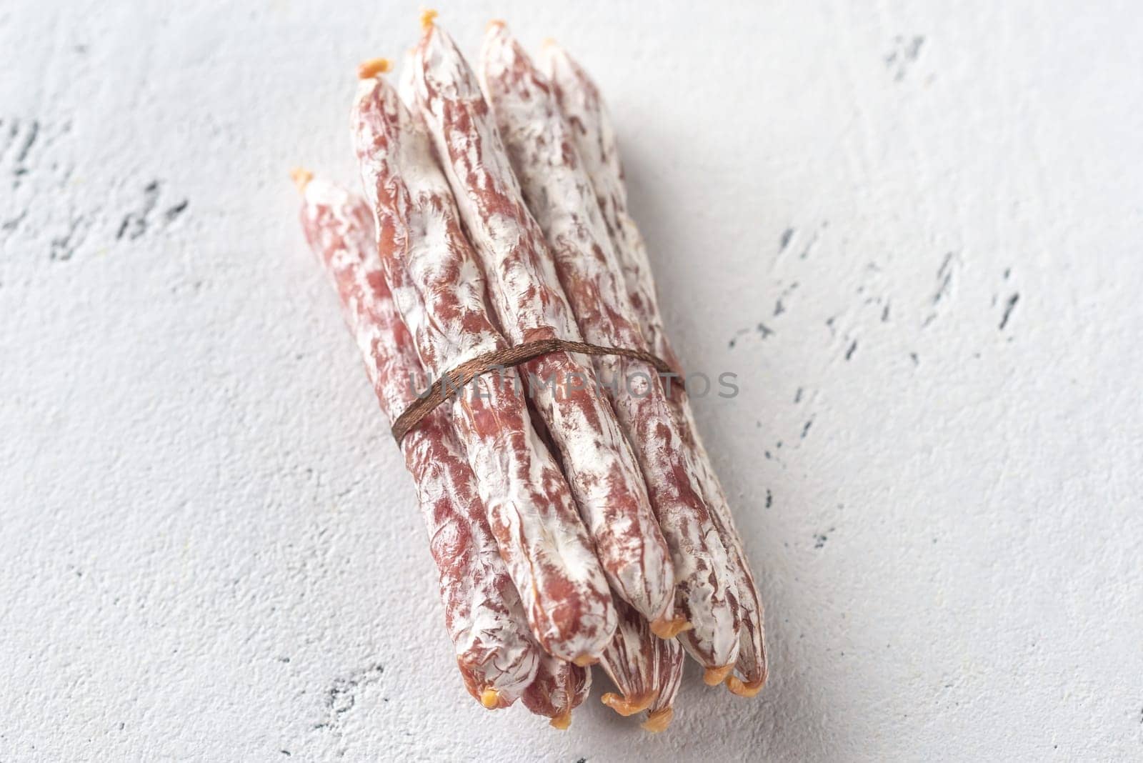 Snack fuet sausages on the wooden background: top view