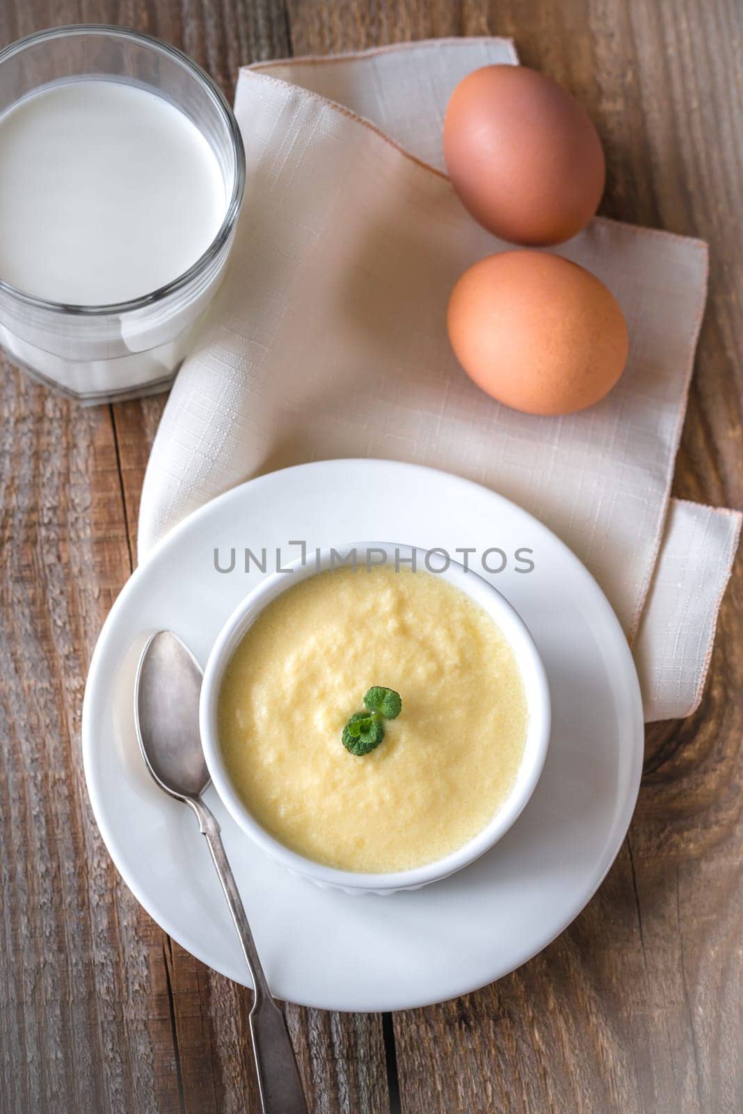 Custard decorated with mint and vanilla pods on the wooden background