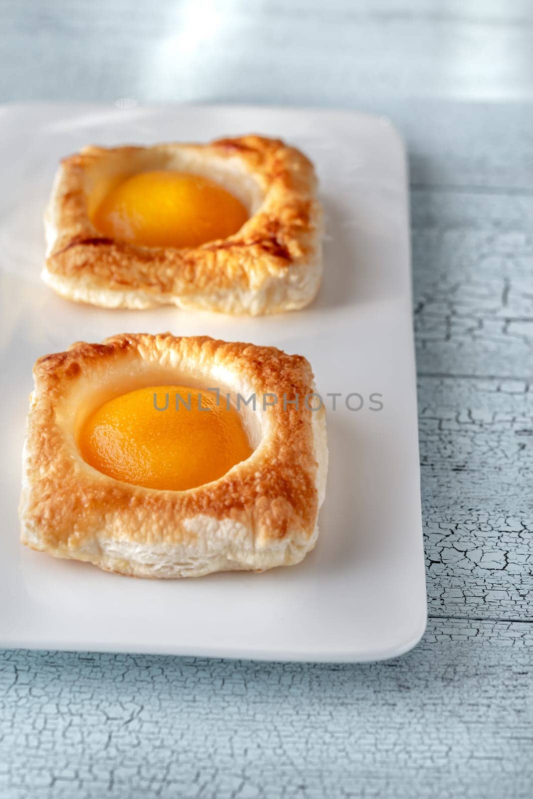 Puff pastry with canned peaches on the wooden table