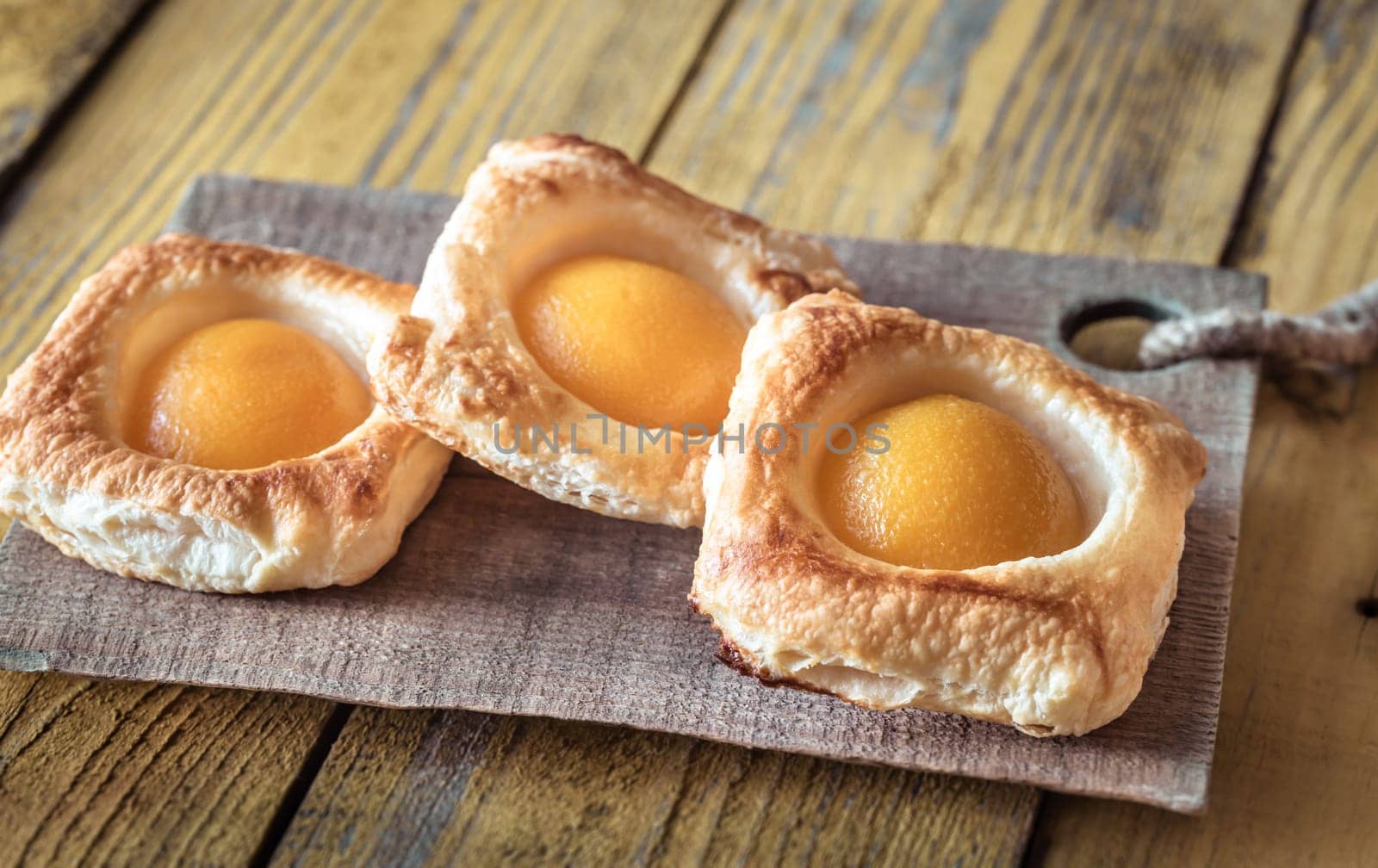 Puff pastry with canned peaches on the wooden table