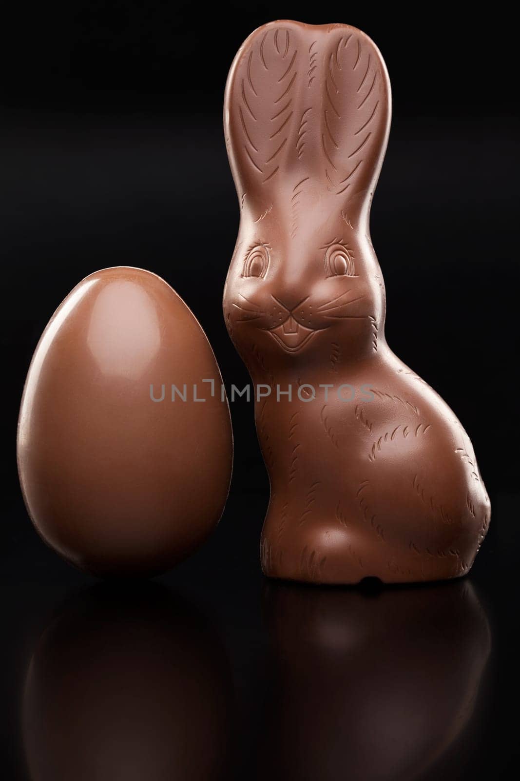 Delicious chocolate Easter bunny, eggs and sweets on rustic background