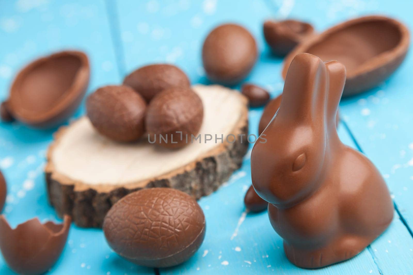 Delicious chocolate Easter bunny, eggs and sweets on rustic background
