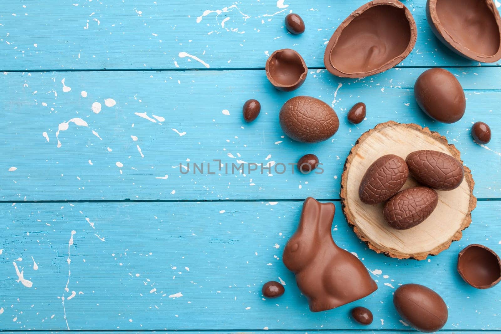Delicious chocolate Easter bunny, eggs and sweets on rustic background