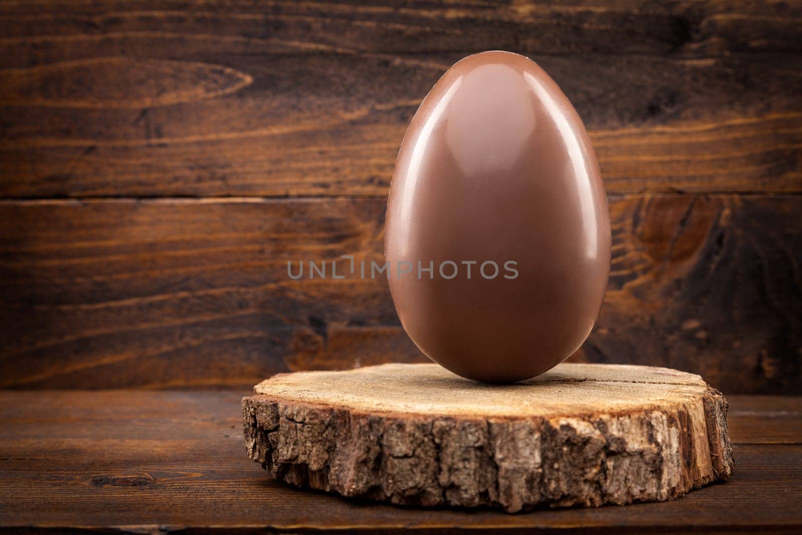 Delicious chocolate Easter holiday egg on rustic background