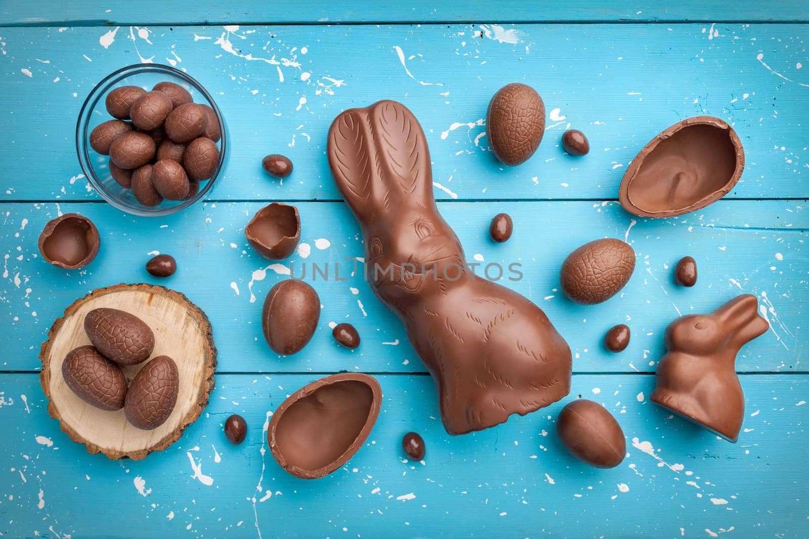 Delicious chocolate Easter bunny, eggs and sweets on rustic background