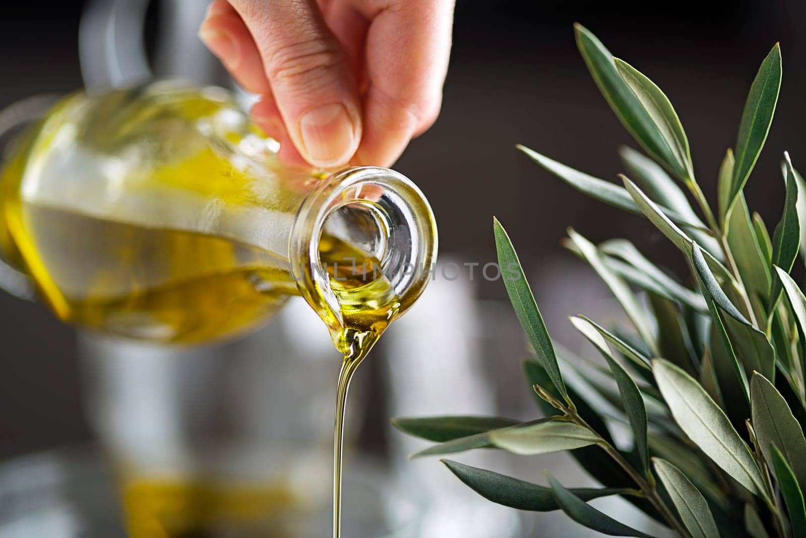 Bottle of virgin olive oil pouring close up