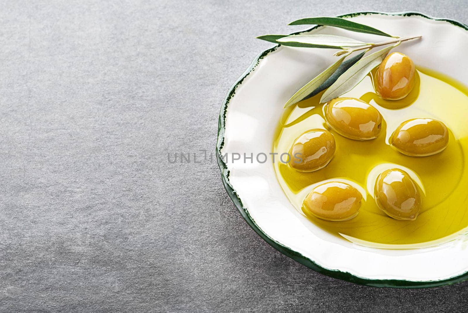 Extra virgin healthy Olive oil with fresh olives in plate close up