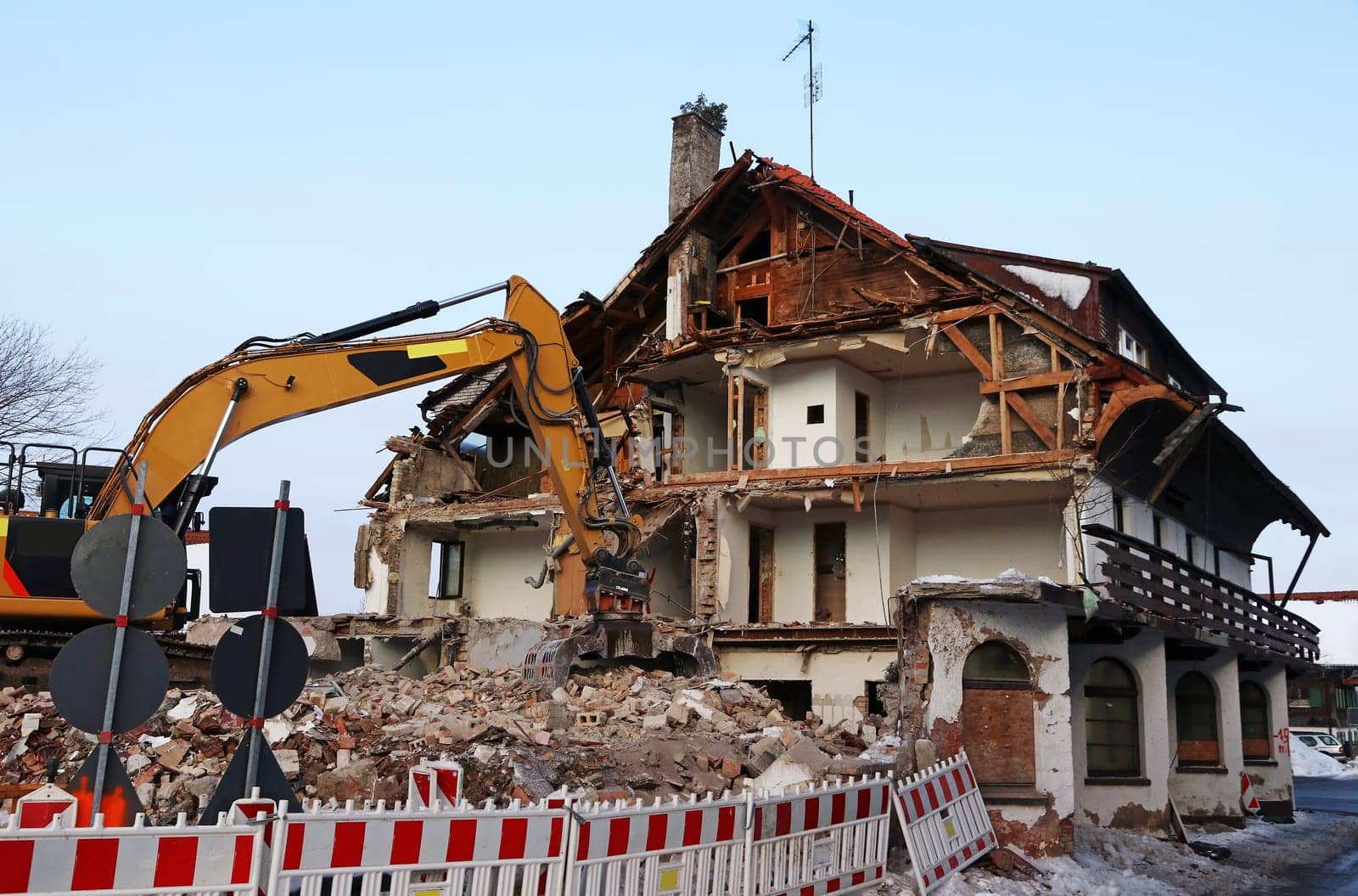An old dilapidated house is torn down with an excavator
