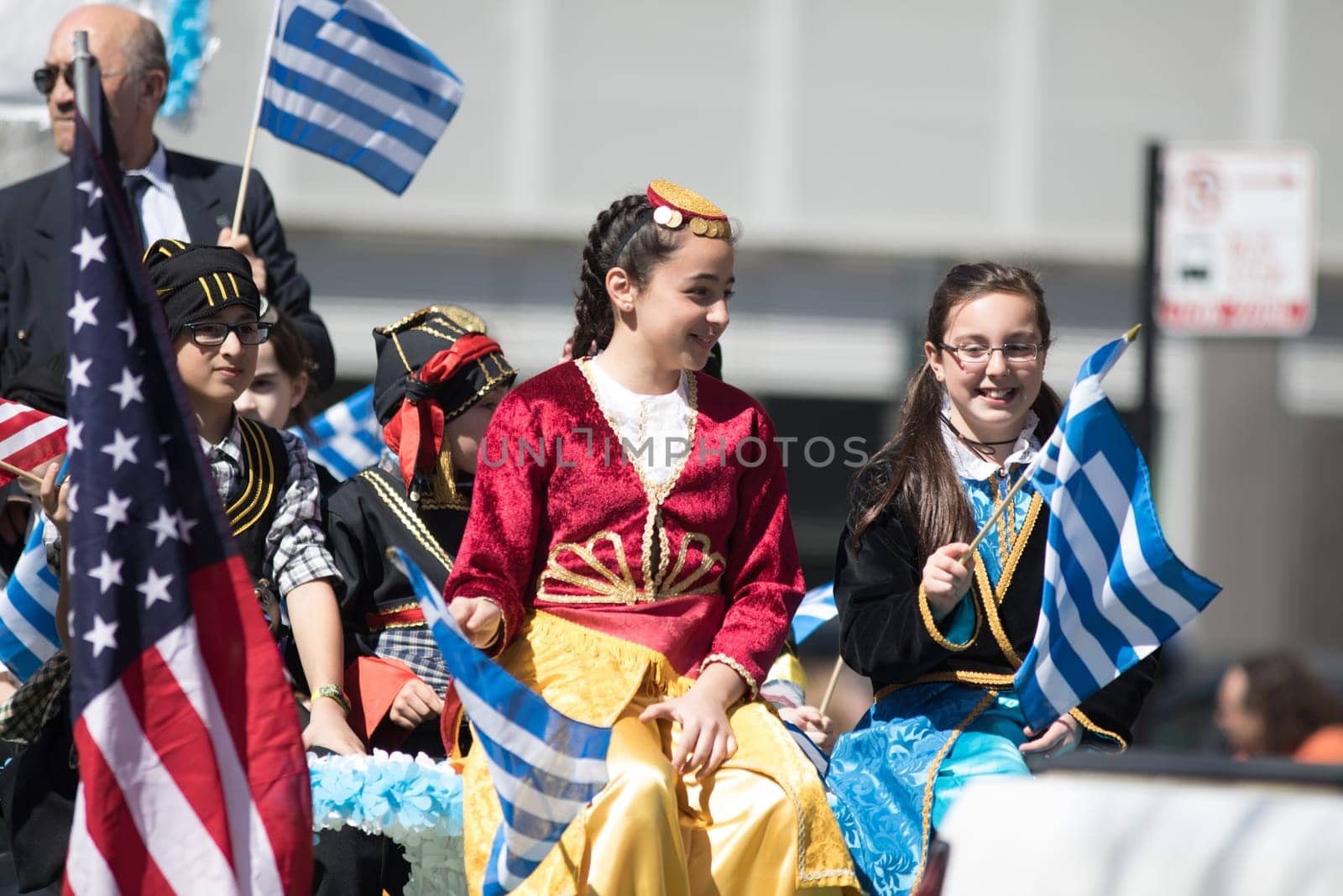 Chicago, Illinois, USA - April 29, 2018 Greek Children wearing traditional clothing waving the greek and usa flag during the Greek Independence  Day Parade