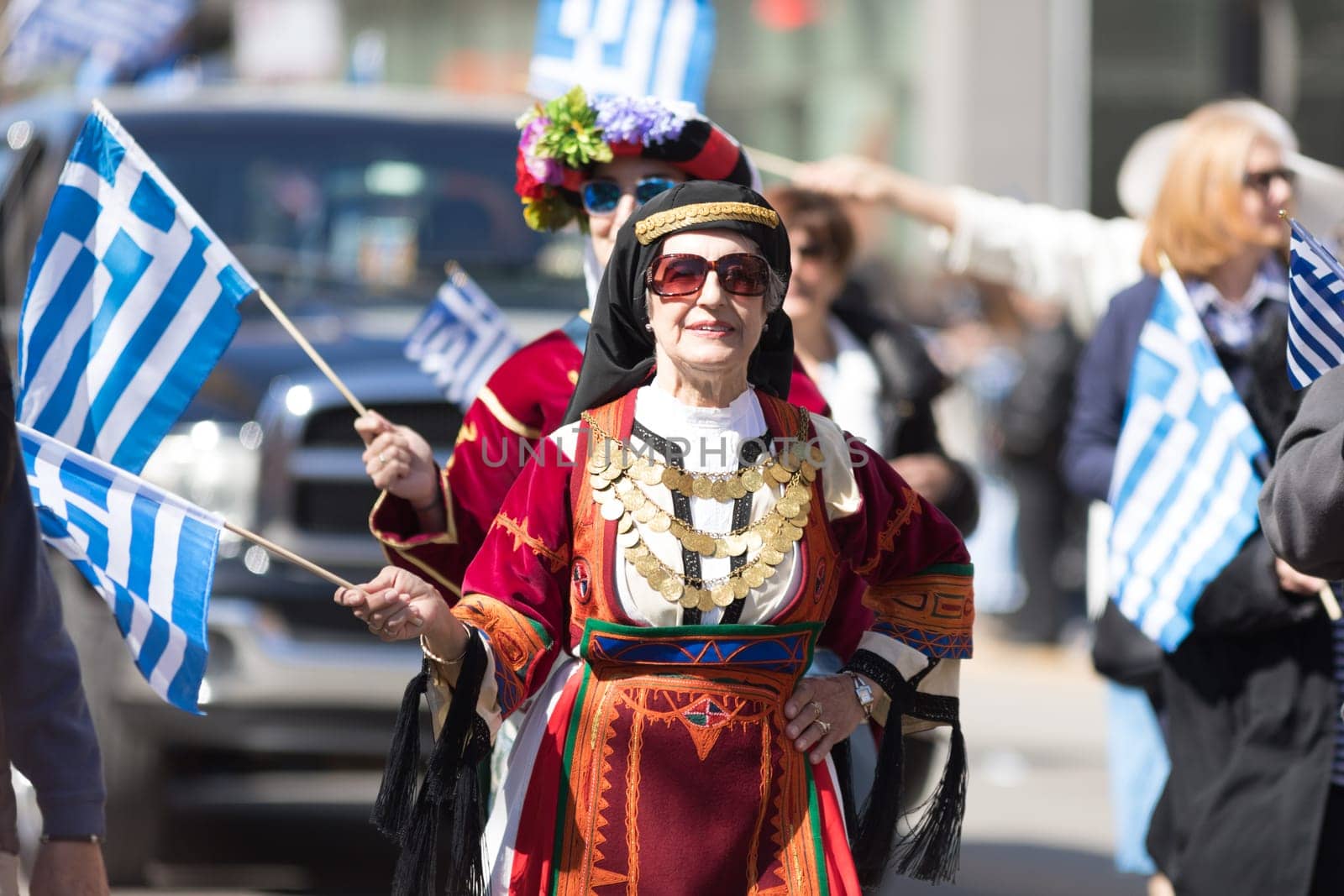 Chicago, Illinois, USA - April 29, 2018  Greek woman wearing traditional clothing waves the greek flag during the Greek Independence  Day Parade