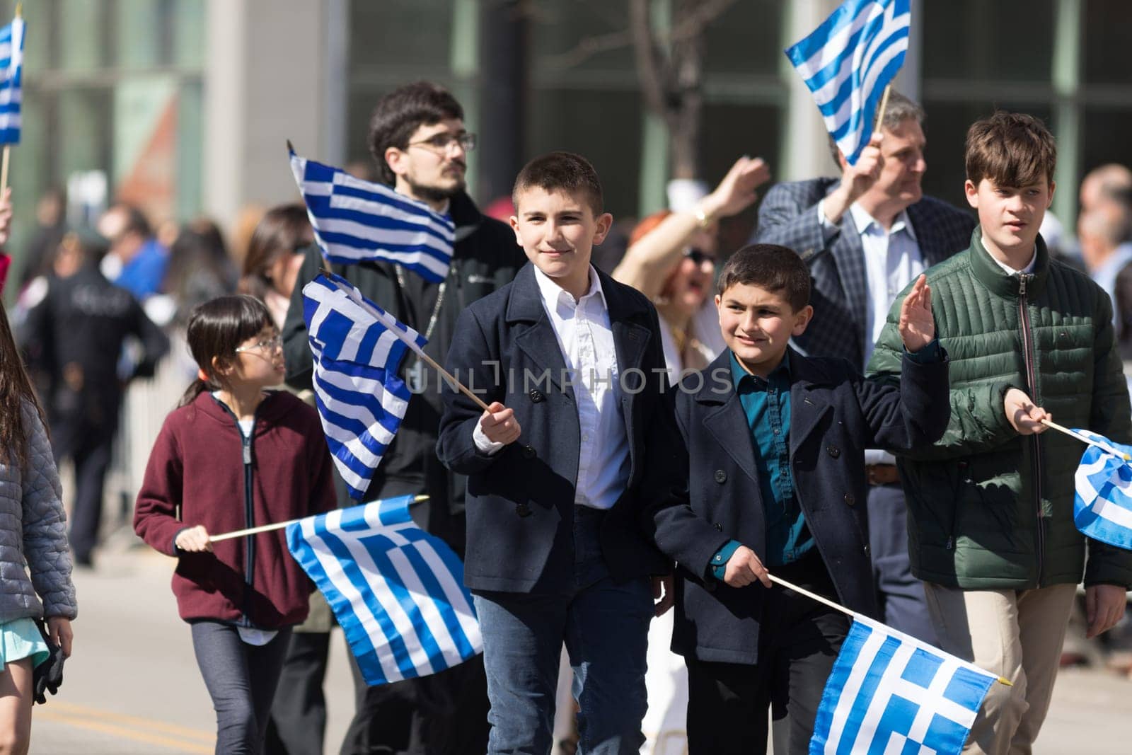 Chicago, Illinois, USA - April 29, 2018 Greek children and adults waving greek flags at the Greek Independence  Day Parade