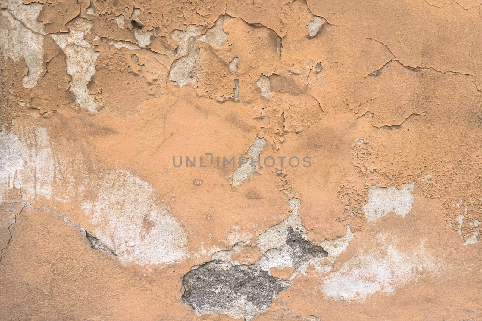 Peeling paint on a dilapidated house wall with cracks. It can be used as concepts or backgrounds.
