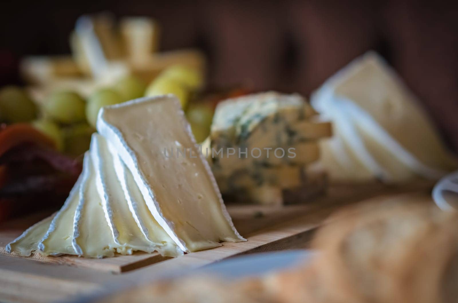 Cheese platter with different cheeses including brie, cheddar and blue cheese, served with grapes