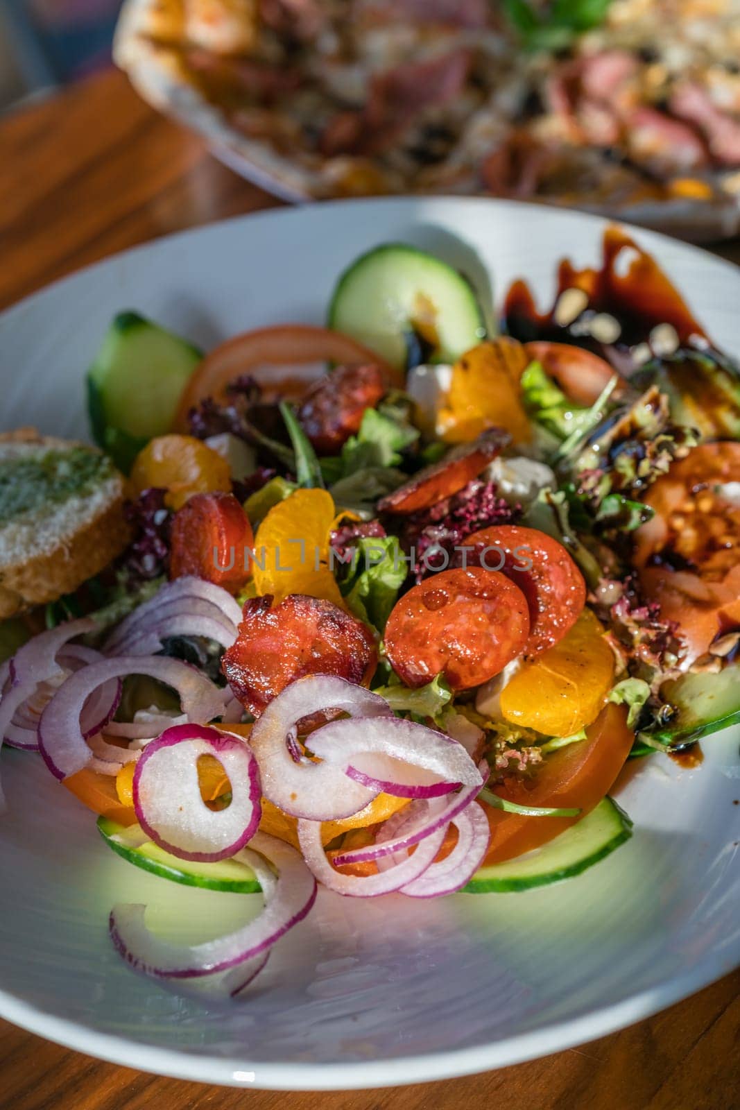 Close-up of a fresh spicy Spanish chorizo summer salad in a white plate
