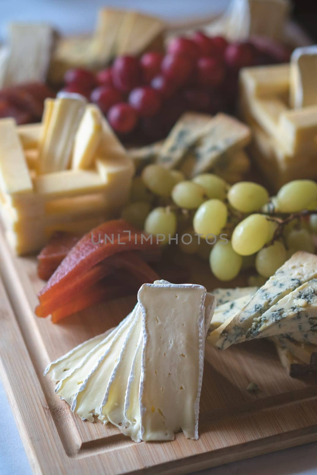 Cheese platter with different cheeses including brie, cheddar and blue cheese, served with grapes