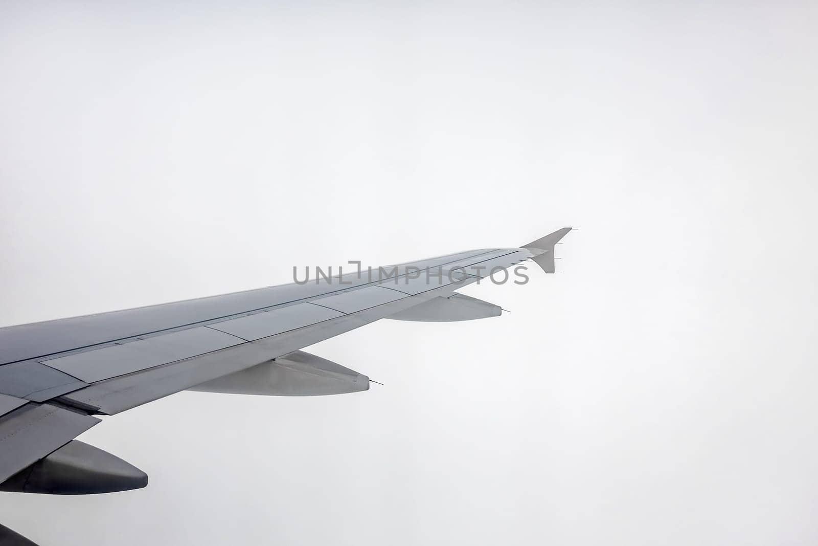 Window view of the wing of an airplane flying into the dense rainy clouds