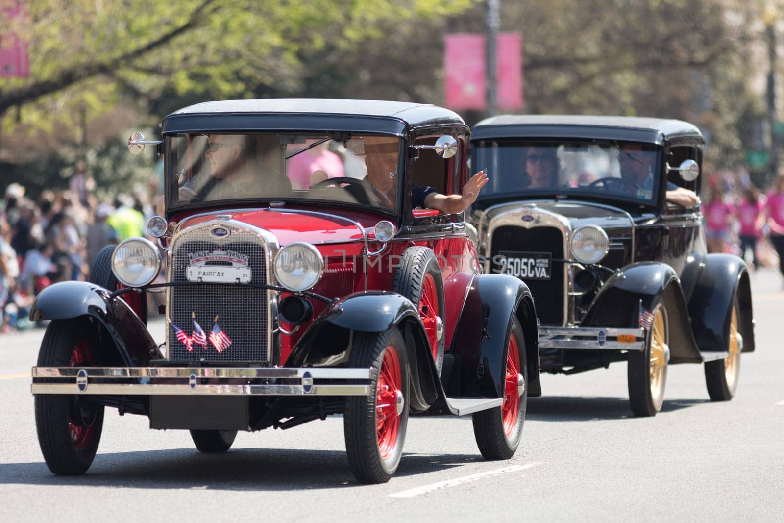 Washington, D.C., USA - April 14, 2018 Classic cars with american flags going down the street in the 2018 National Cherry Blossom Parade