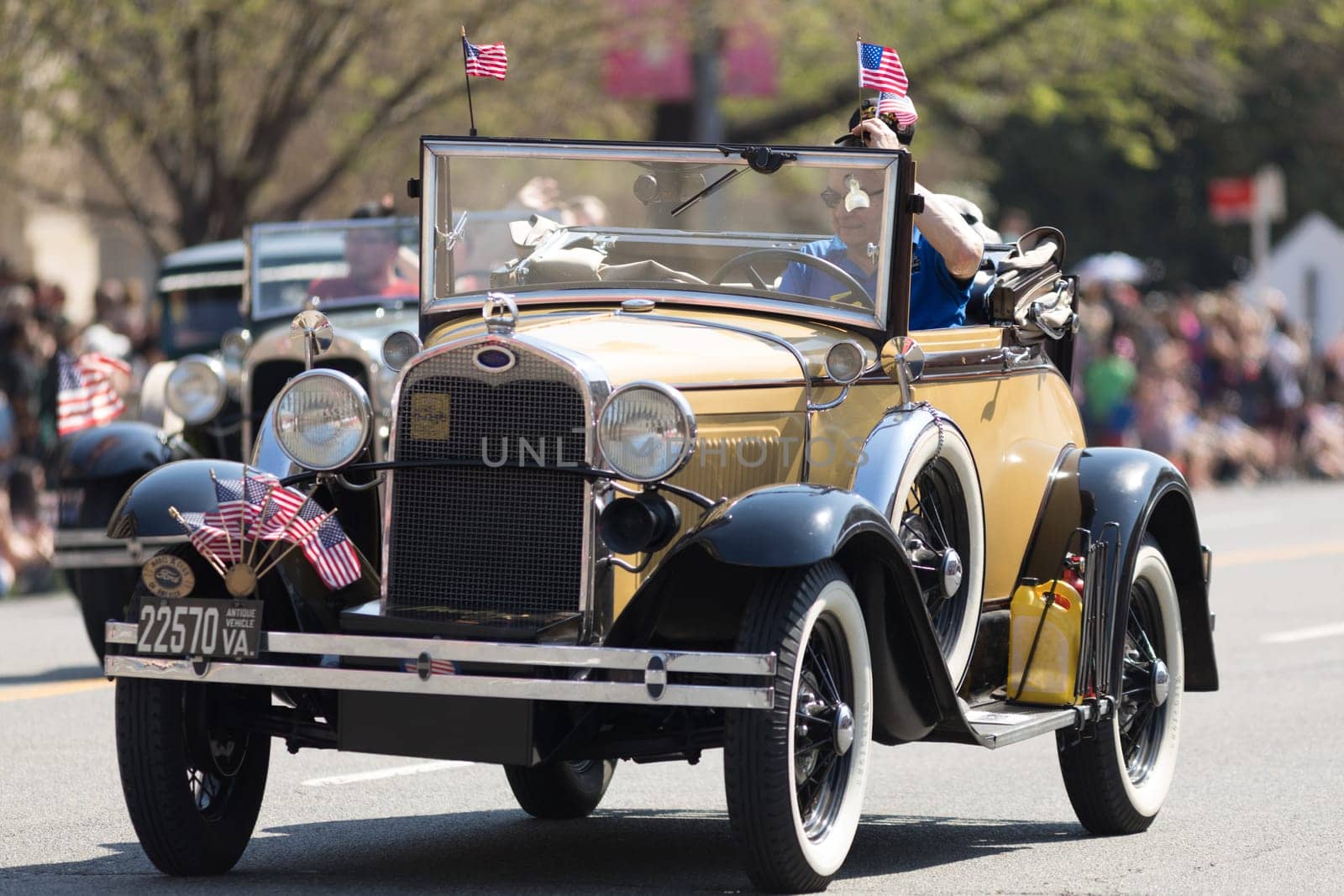 Washington, D.C., USA - April 14, 2018 Classic cars with american flags going down the street in the 2018 National Cherry Blossom Parade